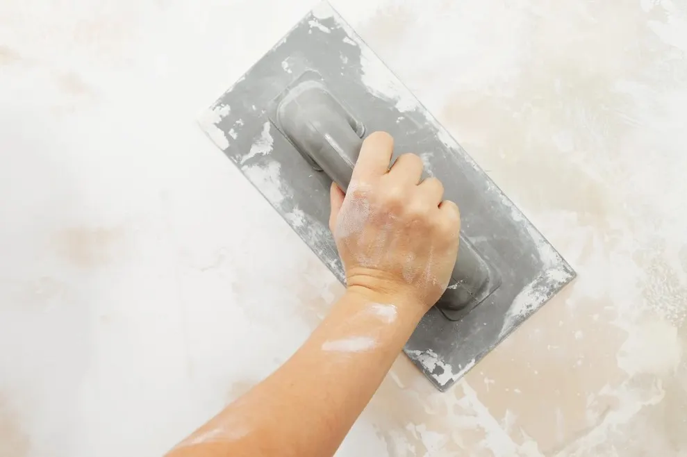 Aplicación de microcemento con llana sobre la pared de un baño en Sahagún