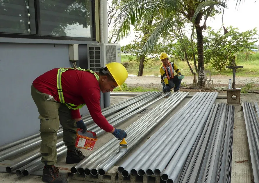 Operario imprimando los perfiles de acero de una estructura metálica antes del montaje