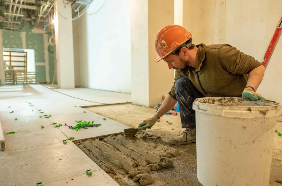 Operario extendiendo el adhesivo con llana dentada para solar el suelo de una vivienda