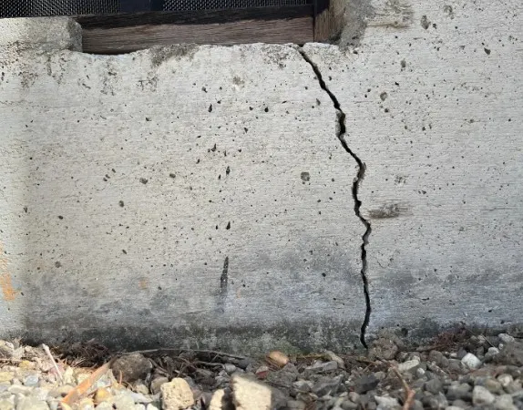 Grieta vertical en un muro de hormigón bajo el alféizar de una ventana, vivienda en San Andrés del Rabanedo