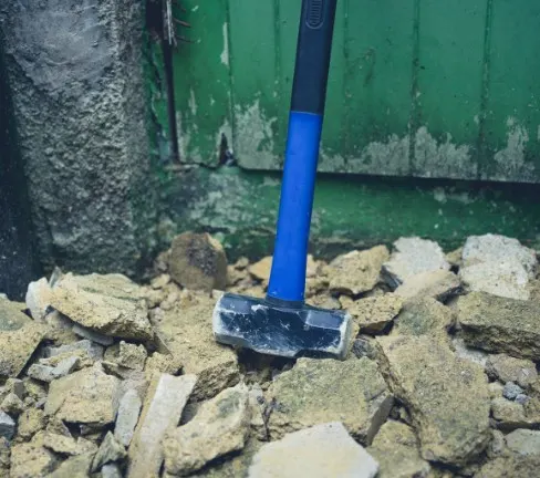 Maza de demolición sobre un montón de escombros de hormigón junto a un poste de piedra, La Virgen del Camino