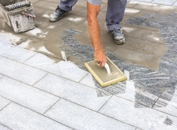 Operario extendiendo y alisando mortero fresco sobre un pavimento exterior