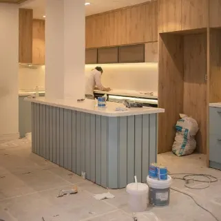 Cocina con isla y muebles de madera en la fase de remates de una reforma integral