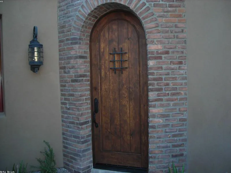 Muro de ladrillo cara vista con puerta de madera en arco