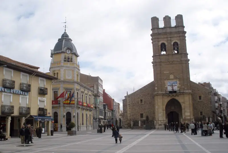 Plaza Mayor de La Bañeza con la torre de la iglesia de El Salvador y edificios con soportales