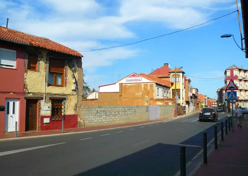 Calle de San Andrés del Rabanedo con una casa antigua de tapial y edificios de ladrillo al fondo