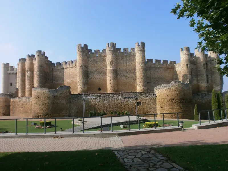 Castillo de Valencia de Don Juan con sus torres cilíndricas y el parque en primer plano